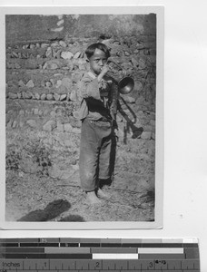 A boy blows a horn in China, 1929