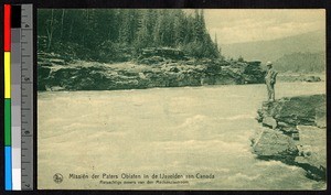 Man standing on rocky outcrop above a river, Canada, ca.1920-1940