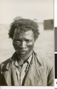 Half figure portrait of an African man wearing a torn European shirt and jacket