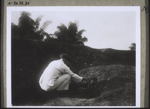 Chinese in front of the grave of his father for whose spirit he burns incense