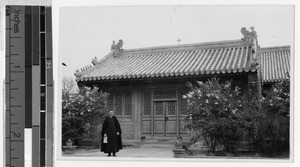 Priest standing in front of a cross-topped building, Beijing, China, ca. 1920-1940