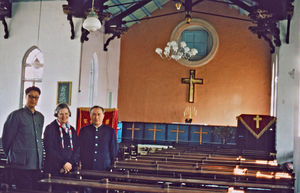 Pens. missionær Rigmor Madsen på besøg i Dongbei, Kina, 1986. Ses her i Dandong gamle kirke, bygget af missionær Emil Jensen i 1915. (Maria Rigmor Madsen er datter af missionærparret Nora og Christian M. Madsen, som arbejdede i Harbin, 1912-28. Hun blev selv sygeplejerske og missionær i Kina fra 1948, men efter kort tid måtte alle missionærer forlade landet. Rigmor Madsen fortsatte så sin tjeneste, først i Sydindien og senere i Tanzania frem til sin pensionering i 1984)