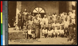 Missionary fathers gathering with others outside a brick building, Congo, ca.1920-1940