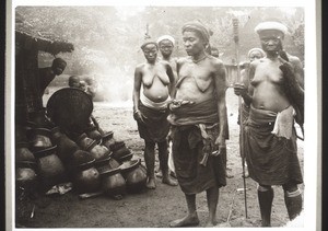 Klageweiber in Nyasoso (Kamerun) je einen Topf vor die Hütte des Verstorbenen legend