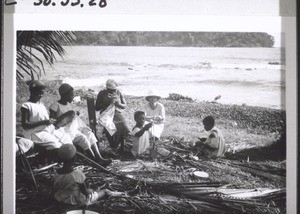 Die Mädchen der Mädchenschule Viktoria verfertigen Besen aus Palmrippen am Meeresstrand, Frln Sarasin schaut ihnen zu