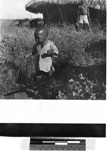 Young boy walking on a path through tall grass, Africa, May 1950