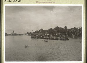 A floating village on the Negara River. A little steamer toes smaller and larger praus. That is the way trade is conducted