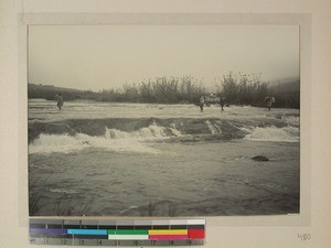 Carriers carefully crossing a river, Madagascar, ca.1900