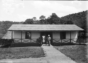 Missionary and Africans in front of a stone house, Tanzania, ca.1893-1920