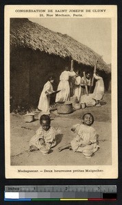 Children eating rice while women grind grain, Madagascar, ca.1900-1930