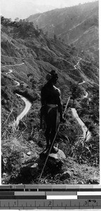 Igorot man looking at a winding mountainside road, Philippines, ca. 1920-1940