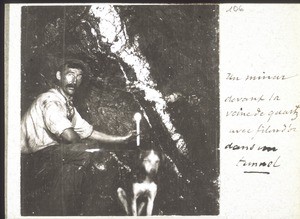 A miner in a tunnel in front of a vein of quartz containing gold