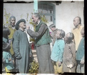 Fr. Anthony Cotta, MM, examining an elderly man's tooth, China, ca. 1906-1919