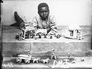 African boy with figurines representing Swiss missionaries, Lemana, South Africa, ca. 1906-1915