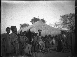 African women and children standing in front of a hut, Antioka, Mozambique, 1923