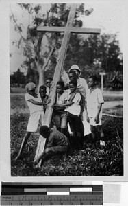 A priest and a group of children putting a crucifix in the ground, Africa, 1936