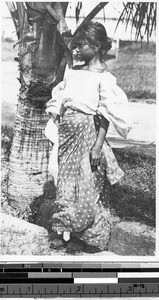 Girl standing next to a palm tree, Philippines, ca. 1920-1940