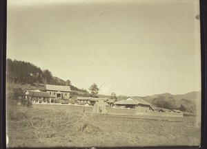 Station Hoschuwan von Südwesten. Am weitesten links das Miss.haus, rechts davon, erhöht, die neue Kapelle, weiter nach rechts die neue Schule. Im Vordergrund die Umfassungsmauer, in dieselbe eingebaut das Ökonomiegebäude