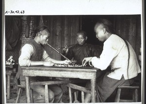 Chinese playing a board-game (and smoking tobacco)