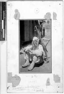 Korean man seated in a street smoking a long pipe, Korea, ca. 1920-1940