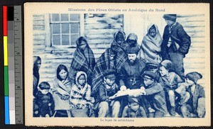 Missionary father teaching people outside of a wooden building, Canada, ca.1920-1940