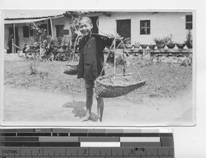 A boy carrying baskets at Dongzhen, China, 1923