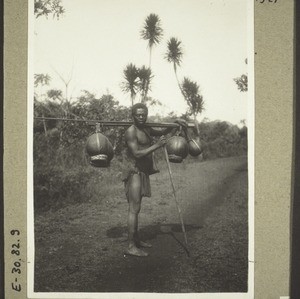 Carrier in Bali with palm oil in calabash-bottles. (1928)