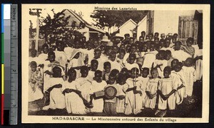 Priest posing with large group of children, Madagascar, ca.1900-1930