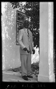 African man ringing a bell in front of a building which is a former movie theater used as a place of worship, Beira, Mozambique, ca. 1940-1950