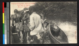 Men standing in a river by a dugout canoe, Cote d'Ivoire, ca.1945