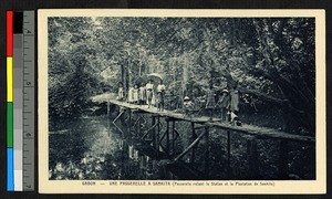 People crossing a low wooden bridge over water, Gabon, ca.1920-1940