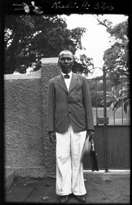 African man standing in front of a gate, Mozambique, ca. 1940-1950