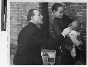 Fr. Meyer helping a mother and child in Guangzhou, China, 1948