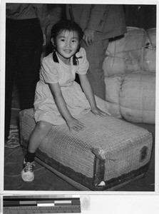 Etsu Nakamura sitting atop a suitcase, Jerome Relocation Center, Denson, Arkansas, September 19, 1943
