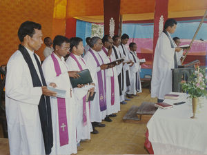 Assam, Nordindien. Mornai Tehaves 100 års jubilæum, juni 1990. Gudstjeneste i forsamlingsbygningen. Fra venstre: Biskop Ruben Murmu, Grahampur, Santal Parganas - Biskop Nityanondo Borgoary, Borokirken - Moderator Sagenen Kisku, Benegaria - Biskop Munshi M. Tudu