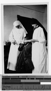 Maryknoll Sisters treating a boy's infected finger, Shingishu, Korea, ca. 1937