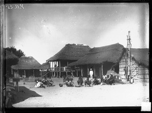 Swiss missionaries and African people in front of buildings with thatched roofs, Mozambique