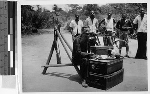 Man sitting eating while others watch, Africa, 1935