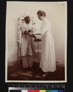 Nurse administering to leper in clinic, Andhra Pradesh, India, ca. 1910-1920