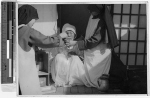 Maryknoll Sisters wash old woman's cancer-infected eye, Yeng You, Korea, ca. 1930-1950