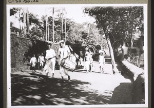 A penitent (woman) is guided through a village