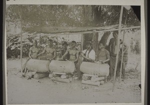 Drummers sitting in a shelter with three talking drums