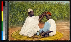 Barber cutting a man's hair, Nigeria, ca.1920-1940