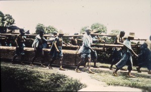 Men carrying a large log, China, ca.1900-1919