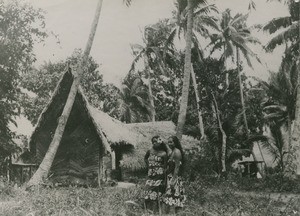 Polynesian women in front of a traditional hut