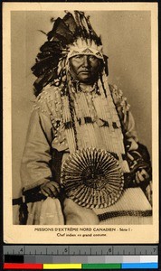 Man wearing elaborate feather headdress and holding a fan, Canada, ca.1920-1940