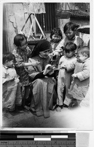 Maryknoll Sister demonstrates a toy to children, Kaying, China, ca. 1940