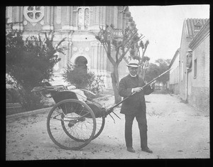 Priest standing with a rickshaw near a church, China, ca. 1918-1938