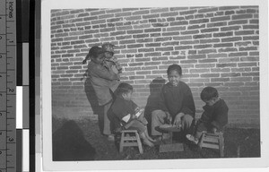 Girl repairing shoes while others watch, Loting, China, ca. 1934