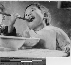 A small child eating rice at Luoding, China